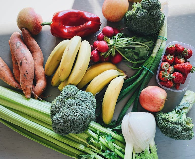 Vibrant mix of fruits and vegetables including bananas, broccoli, and strawberries on display.